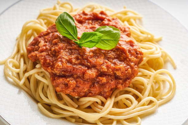 Traditional pasta bolognese served on a white plate and garnished with basil stock photo
