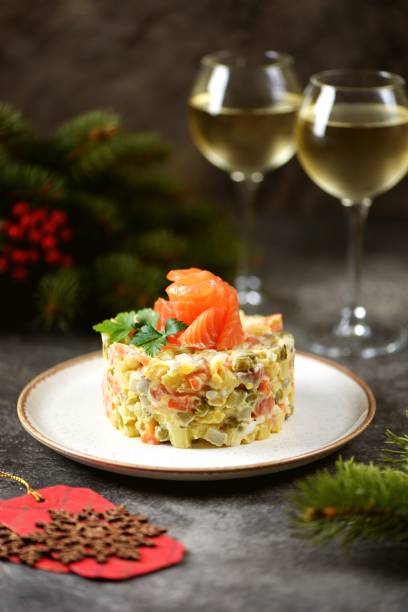 Traditional Russian festive salad Olivier with lightly salted salmon the blurred Christmas lights. stock photo