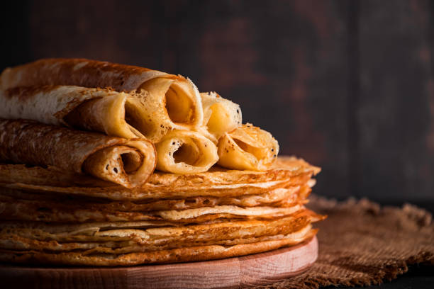 Traditional Russian food - thin pancakes. A stack of crepes on a dark brown wooden background. Rustic style. stock photo