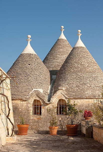 Traditional Trulli house near Locorotondo, Puglia, Italy "Image of a traditional Trulli house near Locorotondo, Province of Bari, Puglia, Italy.  Image sunlit, and shot against the blue summer sky." puglia stock pictures, royalty-free photos & images