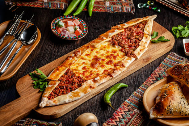 Traditional Turkish cuisine. Turkish pizza Pita with a different stuffing, meat, cheese, slices of veal. Turk Pidesi or Sucuk Pide. Serving dishes in the restaurant. Copy space stock photo