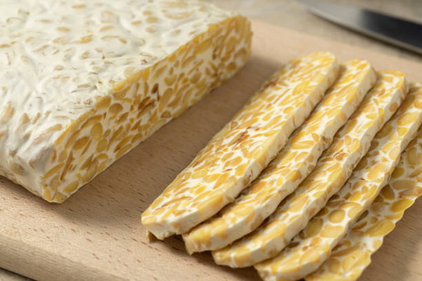 Traditional vegetarian tempeh sliced on a cutting board close up stock photo