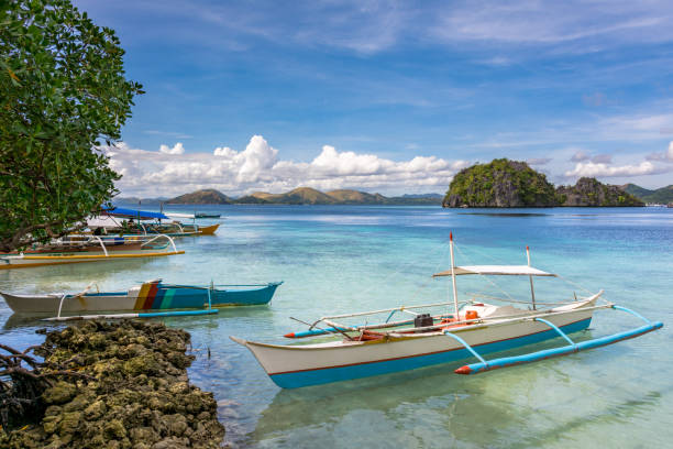 Traditional wooden Filipino boats by the beach of a small island in the sea, Coron Palawan Philippines stock photo