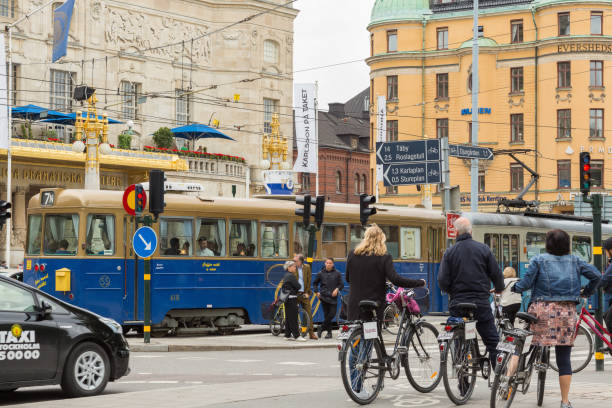 traffic in city center. tram, people, taxi and bike riders. stockholm, sweden - taxi' stockfoto's en -beelden