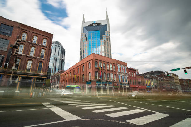 Traffic in motion at an intersection on Broadway looking towards the AT&T Building (The Batman building) Nashville, Tennessee - March 25, 2019 : Traffic in motion at an intersection on Broadway looking towards the AT&T Building (The Batman building) broadway nashville stock pictures, royalty-free photos & images