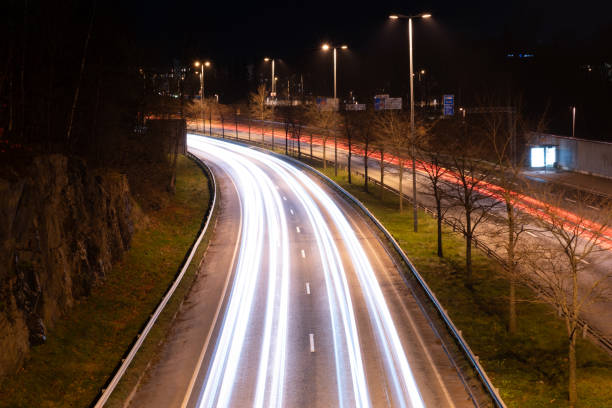 Traffic light trails of bypassing vehicles on the busy highway during nighttime. stock photo