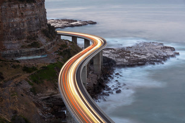 Traffic on Bridge Car light trails on Sea Cliff Bridge, a balanced cantilever bridge located south of Sydney, New South Wales, Australia overpass road stock pictures, royalty-free photos & images