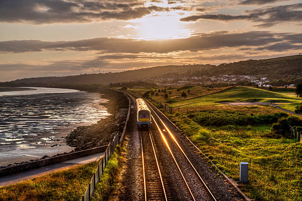 Train travelling past sea wall at sunset stock photo