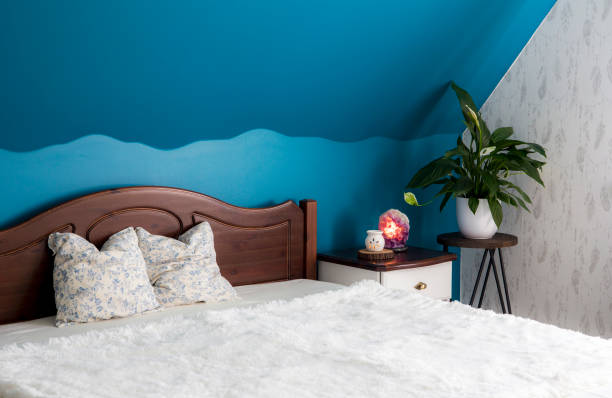 Tranquil blue color bedroom concept. Air cleaning plant Spathiphyllum on flower stand, Amethyst crystal lamp illuminated and aroma lamp for relaxing aromatherapy. Natural wood furniture. Tranquil blue color bedroom concept. Air cleaning plant Spathiphyllum on flower stand, Amethyst crystal lamp illuminated and aroma lamp for relaxing aromatherapy. Natural wood furniture. feng shui bedroom stock pictures, royalty-free photos & images