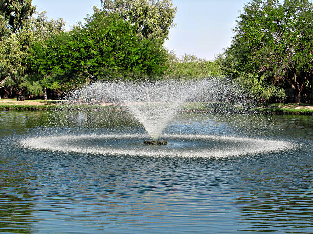 Tranquil Fountain A beautiful fountain sprinkles water in a small pond fountain stock pictures, royalty-free photos & images