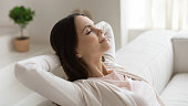 istock Tranquil millennial female napping on couch with hands behind head 1310961723