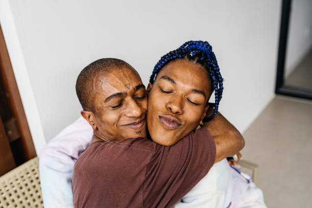Trans woman and non-binary person hug each other affectionately stock photo