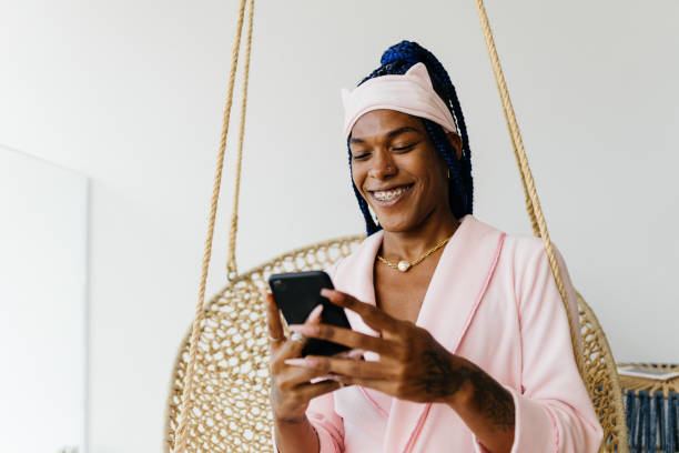 Trans woman using smartphone at home stock photo