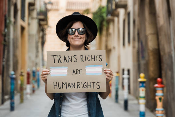 Transgender hipster woman fighting for transsexual human rights at gay pride holding banner - People celebrating lgbt event concept - Focus on sign stock photo
