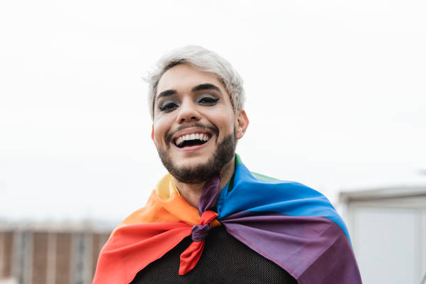 Transgender man wearing LGBT rainbow flag outdoor - Focus on gay male face stock photo