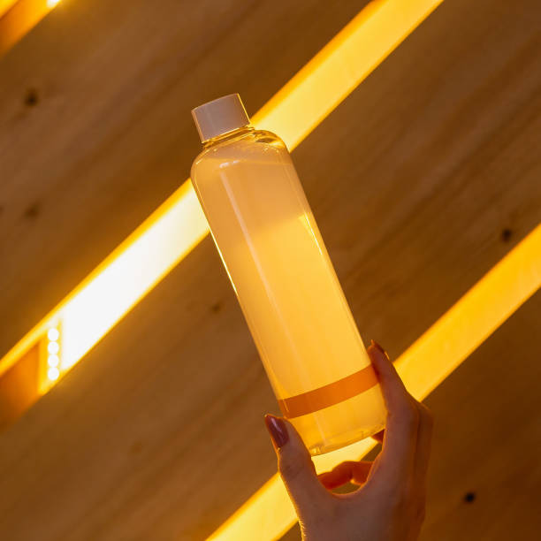 Transparent orange bottle with shampoo or lotion in a woman's hand stock photo