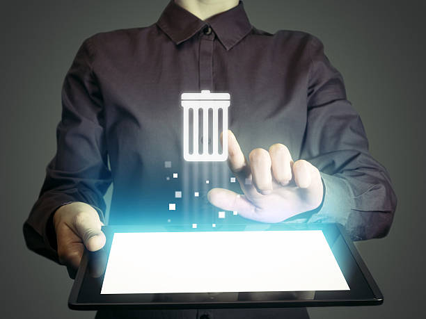trash can Image of a girl with tablet in her hands. She presses trash can icon. The concept of deleting files, contacts, putting in order, cleaning service etc garbage photos stock pictures, royalty-free photos & images
