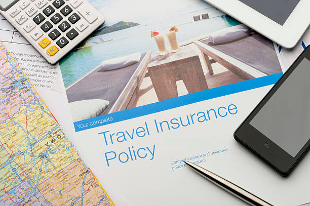 書類と技術を含む旅行保険契約書類。カクテルを飲む観光リゾートや、安心のコンセプトを望むスイミングプールをイメージしています。携帯電話、地図、デジタルタブレット、電卓もあります。パンフレットに掲載されている画像は、ポートフォリオ20943516