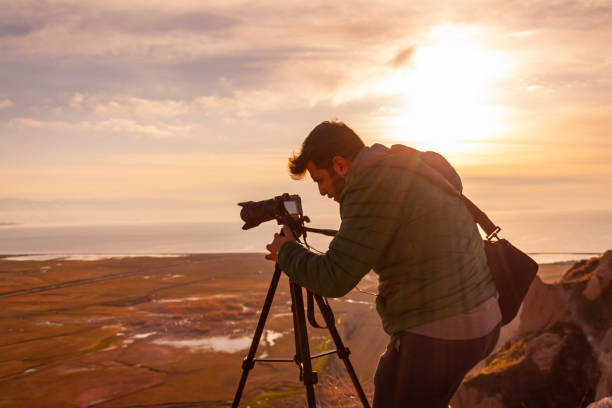 Travel photographer man taking nature video of sunset landscape stock photo