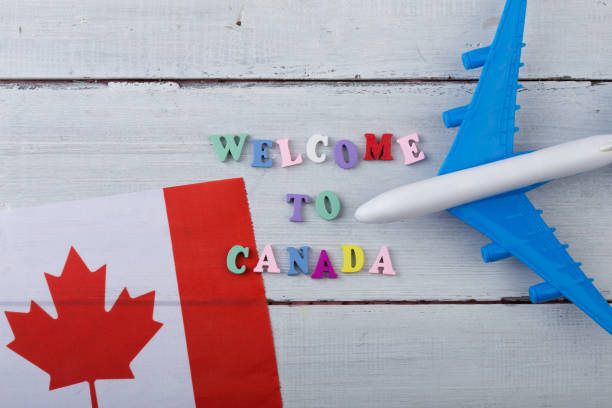 Travel time - colorful wooden letters with text "Welcome to Canada" , flag of the Canada, airplane model, passport stock photo
