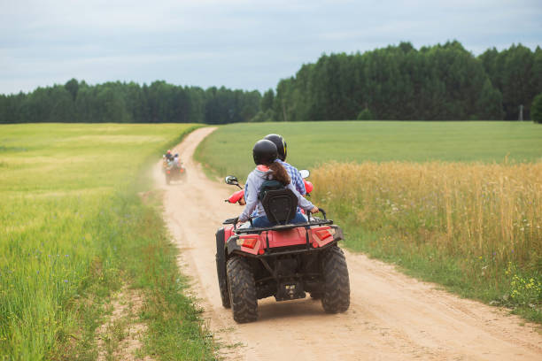 Travel tour on qad bikes in the beautiful wheat field roads. Couple riding in ATV back view stock photo