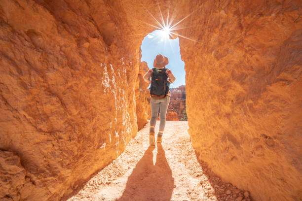 Travel woman explores canyon with backpack on shoulders; people discovery travel destinations concept. Girl walking through tunnel in Bryce Canyon Travel woman explores canyon with backpack on shoulders; people discovery travel destinations concept. Girl walking through tunnel in Bryce Canyon bryce canyon national park stock pictures, royalty-free photos & images