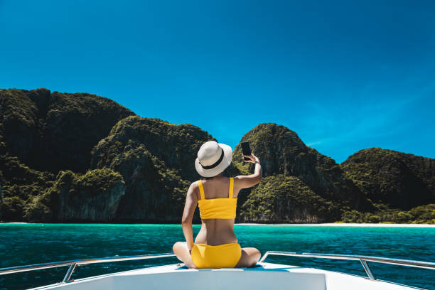 traveler asian bikini woman with mobile phone travel on boat in maya bay phuket thailand - maya bay imagens e fotografias de stock
