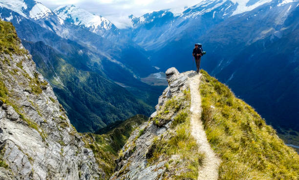 traveler at the edge of a cliff with amazing view behind him traveler at the edge of a cliff with amazing view behind him.Cascade Saddle, Mount Aspiring National Park, New Zealand new zealand stock pictures, royalty-free photos & images