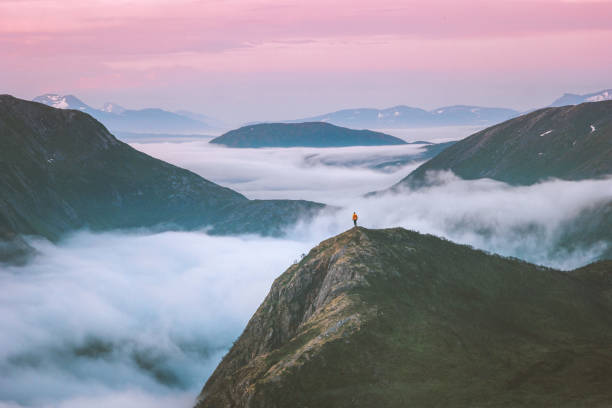 Traveler hiking above mountain clouds enjoying Norway sunset landscape travel adventure lifestyle vacation outdoor epic trip stock photo