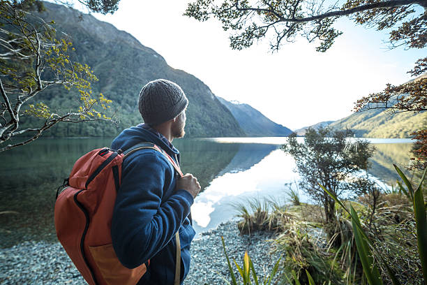 Traveler man by the mountain lake contemplates beautiful landscape stock photo