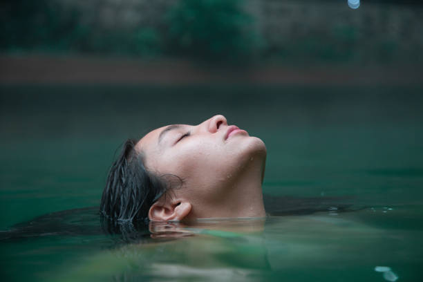 Traveler woman enjoying a spa day in natural hot springs - Hispanic young woman Submerged Up To Her Face in Water with eyes closed submerged woman up to the neck in hot springs in guatemala hot peruvian women stock pictures, royalty-free photos & images