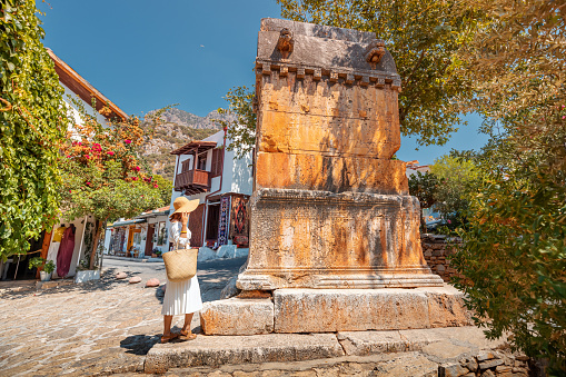 Traveler woman explores Lycian King tomb on the streets of the small tourist town of Kas. Sightseeing and vacation in Turkey