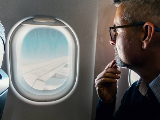 Traveling by airplane Close-up of passenger looking out through window on a plane plane window seat stock pictures, royalty-free photos & images