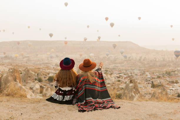 Traveling women wearing authentic boho chic style poncho, sweeter and hats looking on air ballons in sky in Cappadocia valley. Travel and wanderlust concept.  hot egyptian women stock pictures, royalty-free photos & images