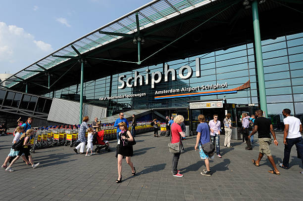 travellers at the entrance of amsterdam airport schiphol - schiphol stockfoto's en -beelden