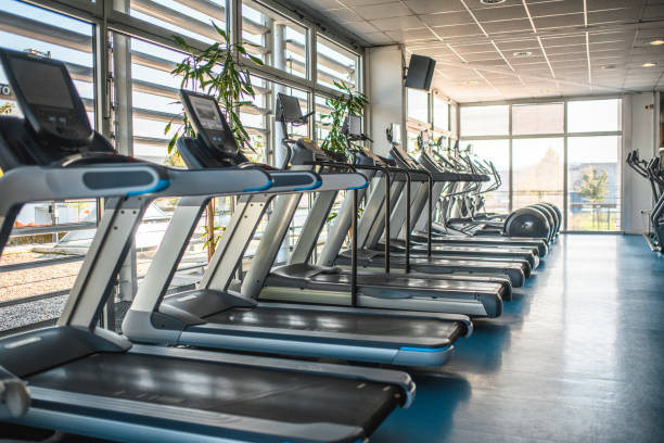 treadmill dan cross trainer berdampingan di gym - pusat kebugaran fasilitas rekreasi potret stok, foto, & gambar bebas royalti