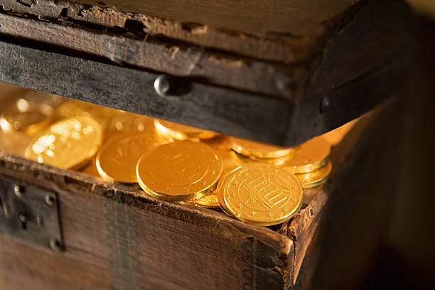 Treasure Chest with Gold Coins Close-Up corner of partially open treasure chest exposing gold coins buried stock pictures, royalty-free photos & images