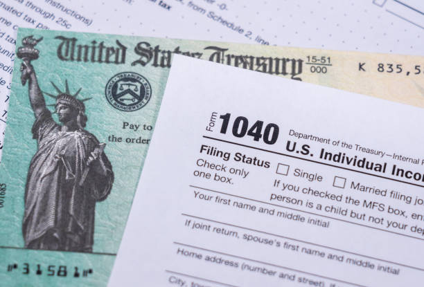 US Treasury check for stimulus in 2020 against a USA Form 1040 US Treasury stimulus check laying on a form 1040 tax return for 2020 to illustrate questions about qualification for payment stimulus check stock pictures, royalty-free photos & images
