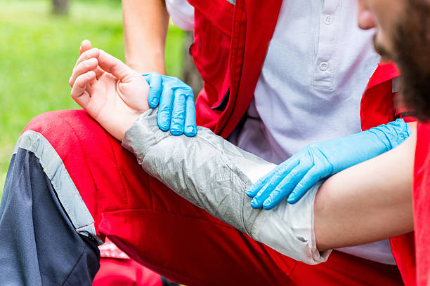 Treating burn injury, putting bandage Medical worker treating burns on man's hand. First aid training burning stock pictures, royalty-free photos & images