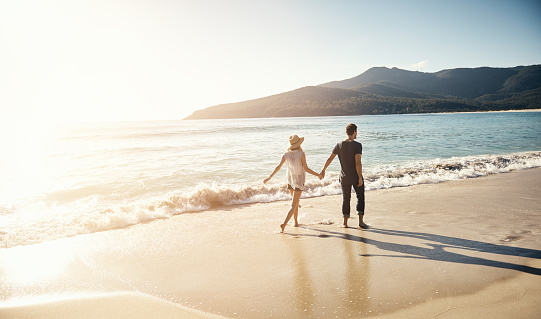 Shot of a young couple going for a stroll along the beach