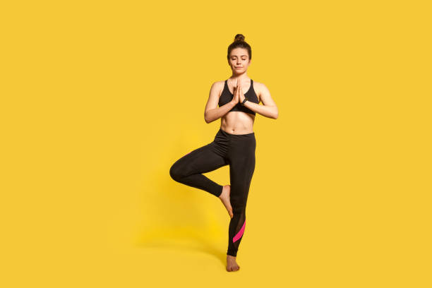 baum pose. athletische schlanke frau mit haar brötchen in engen sportbekleidung üben yoga, vrksasana übung - yoga poses stock-fotos und bilder