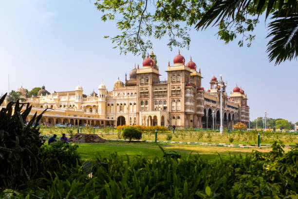 Trees framing a view of the Mysore palace, India Trees framing a view of the Mysore palace with unrecognisable people far in the background, India mysore stock pictures, royalty-free photos & images