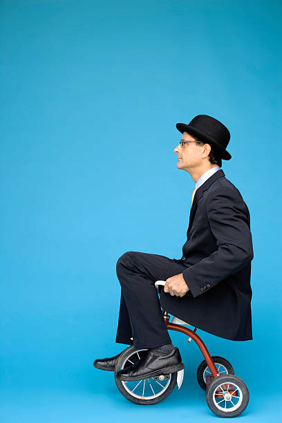 Tricycle Businessman Businessman in bowler hat riding tricycle. adult tricycle stock pictures, royalty-free photos & images