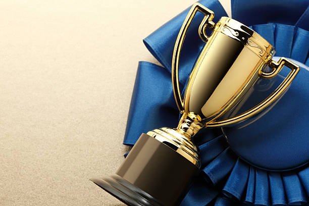 Trophy and Blue Ribbon A blue ribbon and a trophy.To see similar images click on the link below: trophy award stock pictures, royalty-free photos & images
