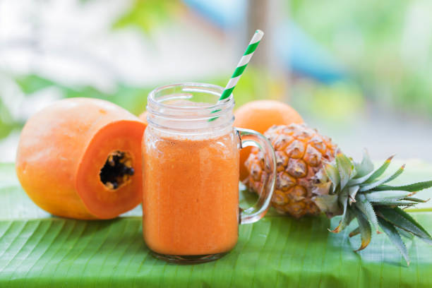 Tropical exotic pineapple and papaya fruits with jar smoothie shake juice drink outdoors with palm leaves Tropical exotic pineapple and papaya fruits with jar smoothie shake juice drink outdoors with palm leaves papaya smoothie stock pictures, royalty-free photos & images