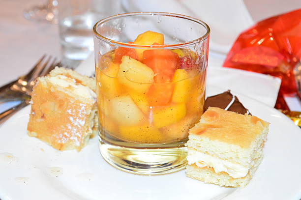 Tropical fruit salad surrounded by cakes stock photo