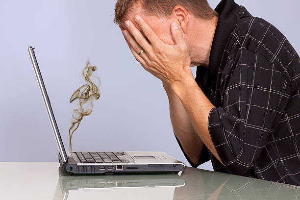 Troubled man with smoking laptop computer stock photo