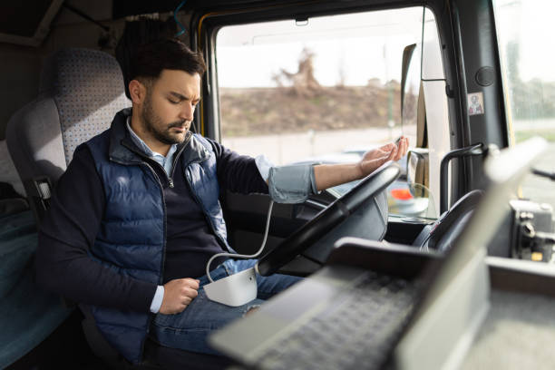 Truck driver sitting in cabin and measuring blood pressure stock photo