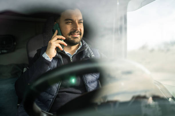 Truck driver sitting in cabin and talking on phone stock photo