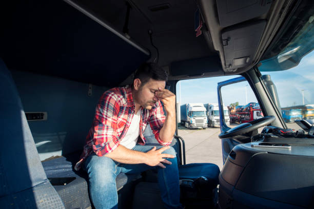 Truck driver sitting in his truck cabin feeling worried and upset. Truck driver lifestyle and problems. Truck driver sitting in his truck cabin feeling worried and upset. Truck driver lifestyle and problems. truck driver stock pictures, royalty-free photos & images